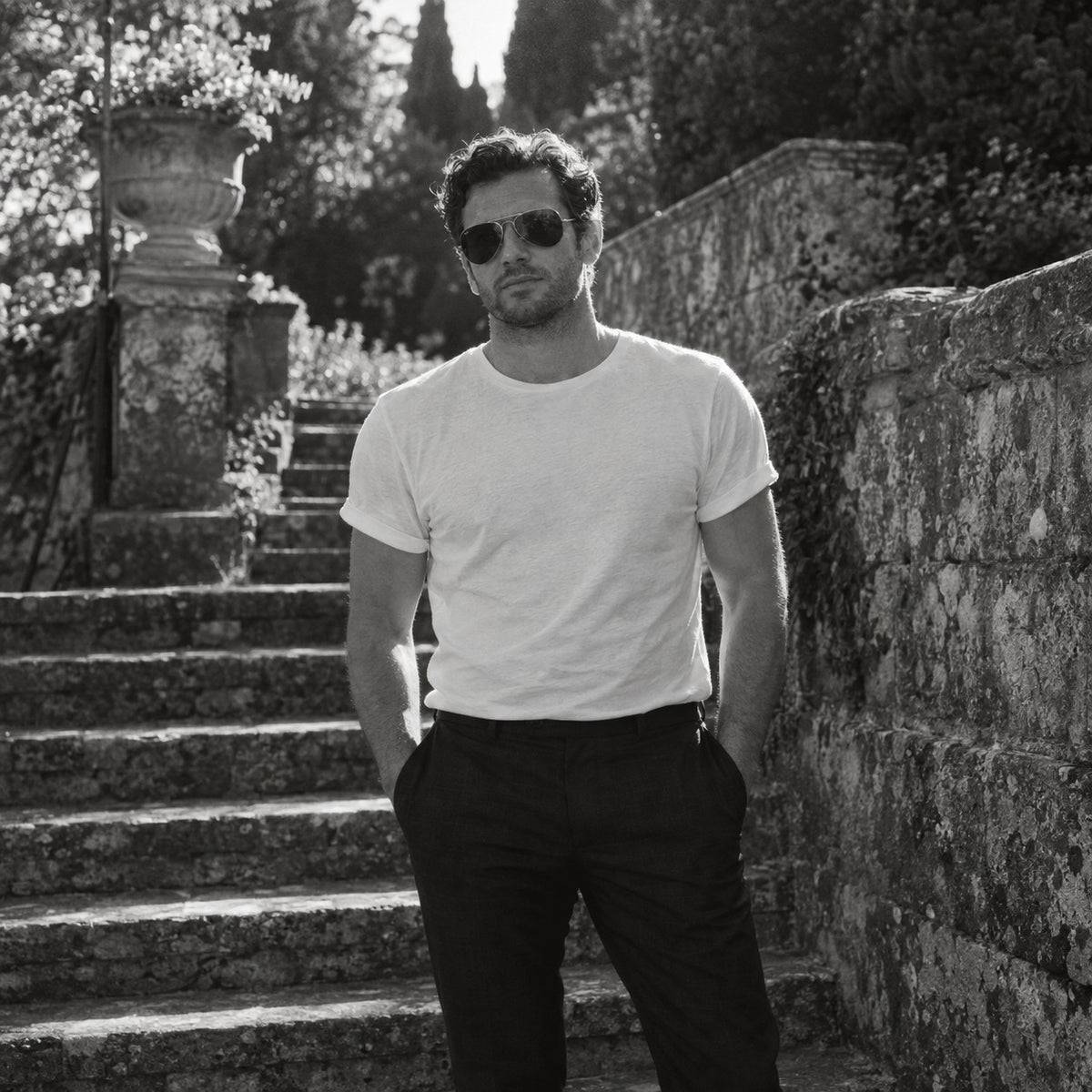 Man in a white t-shirt and dark trousers outdoors in spring light, black and white
