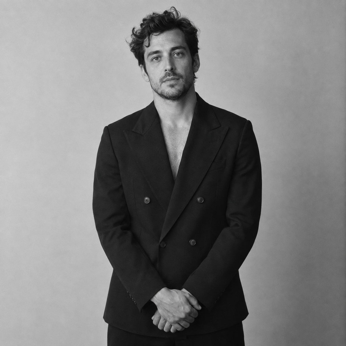 Man in a tailored black double-breasted blazer, black and white studio portrait
