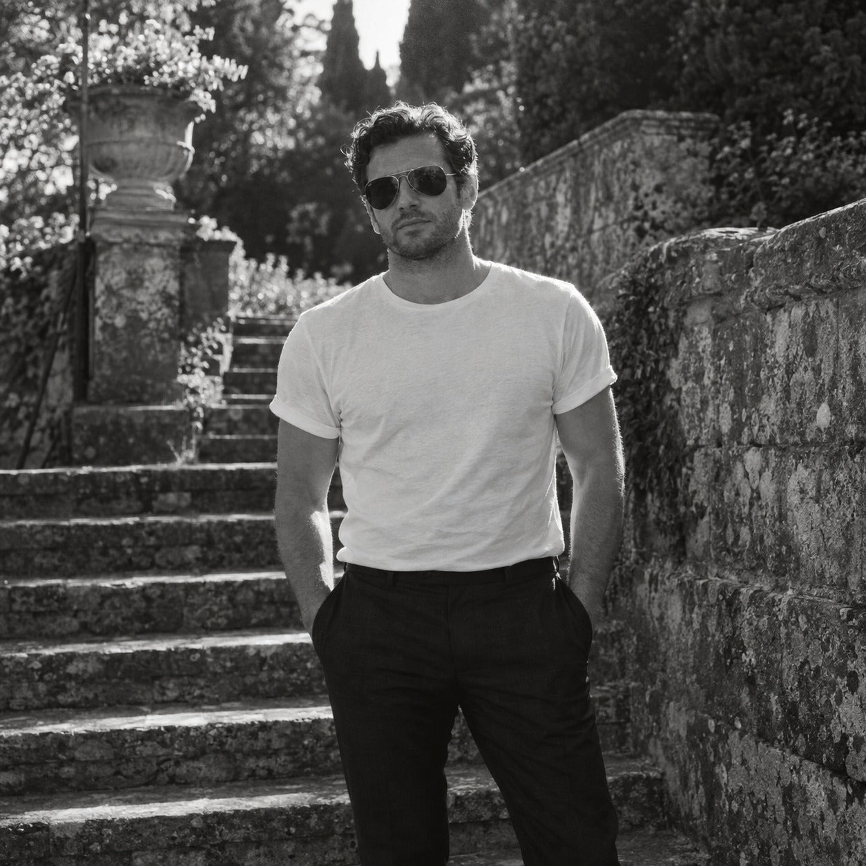 Man in a white t-shirt and dark trousers outdoors in spring light, black and white